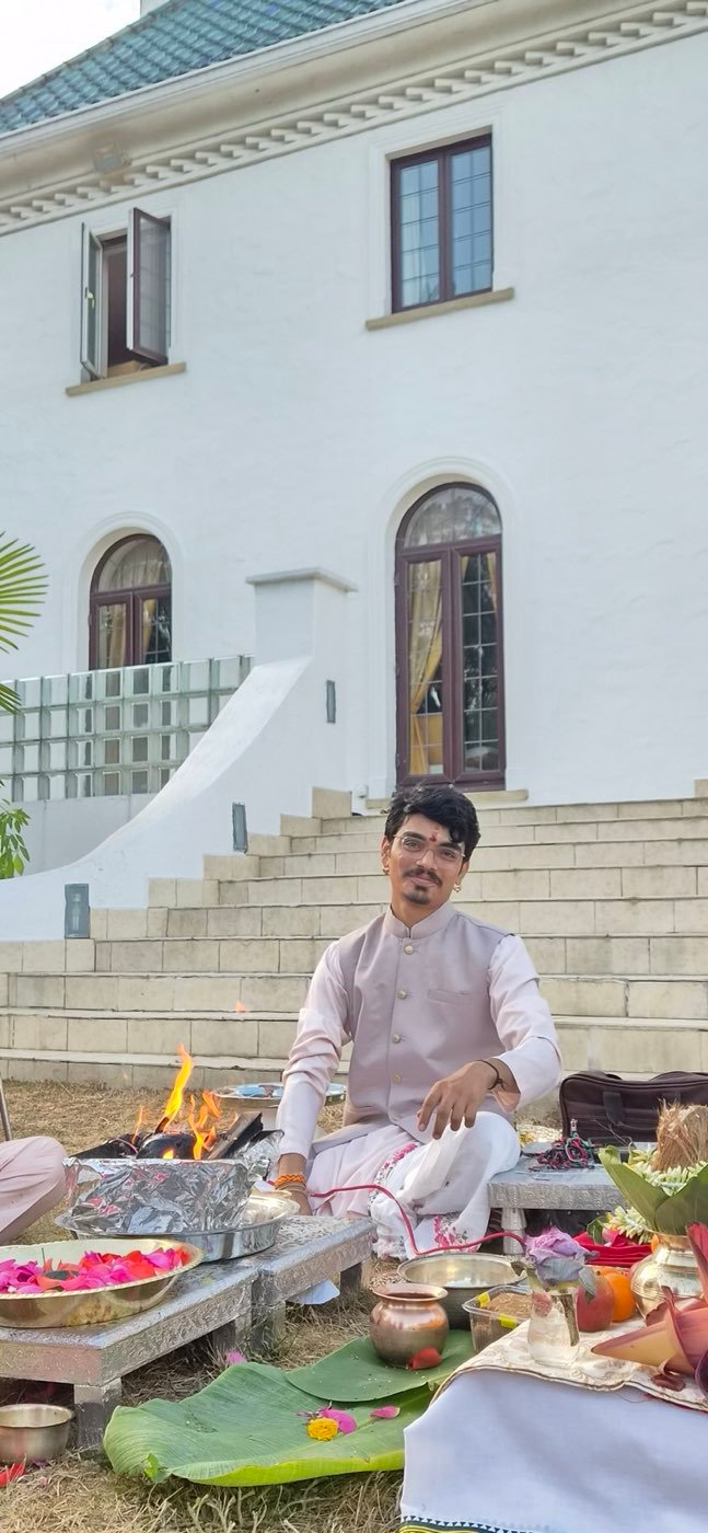 Parth Bhatt seated at a havan in front of a white house, with the fire lit and offerings laid out